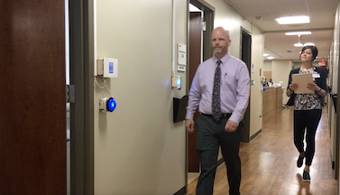 GaitRate wall-mounted device in clinic setting with man walking by sensor and woman following